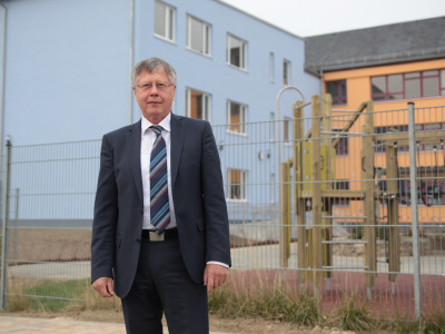 Thomas Fügmann, Landrat Saale Orla Kreis, setzte sich entscheidend für die Umsetzung des Schulzentrum-Projektes als ÖPP-Projekt ein. (im Bild: Thomas Fügmann vor dem Schulneubau)