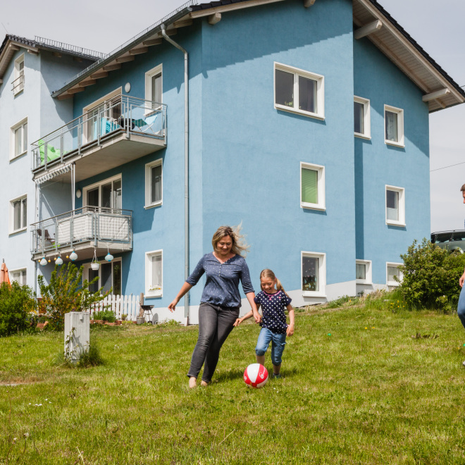 Eine Familie spielt Fußball vor dem Eigenheim